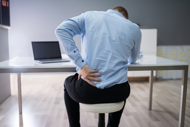 上班族长时间坐办公桌，若坐姿不良、操作电脑姿势不正确，很容易引起背痛。（示意图／Shutterstock）