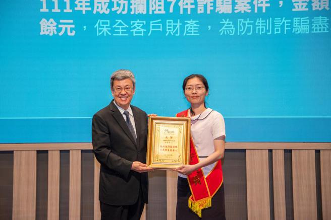 銀行公會於5月11日舉辦「金融業打擊詐欺高峰會」，會中表揚全國10位臨櫃關懷提問成效優異的基層行員，中華郵政公司由彰化光復路郵局襄理李容慈(右)代表接受行政院院長陳建仁(左)頒獎。圖／中華郵政公司提供
