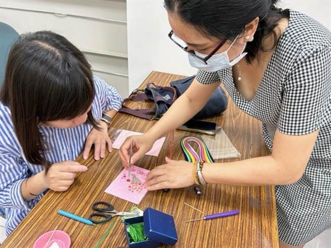 越南及新住民范玉映（右）教大家如何利用纸片卷出各式立体图案。（移民署台南市第一服务站提供／程炳璋台南传真）