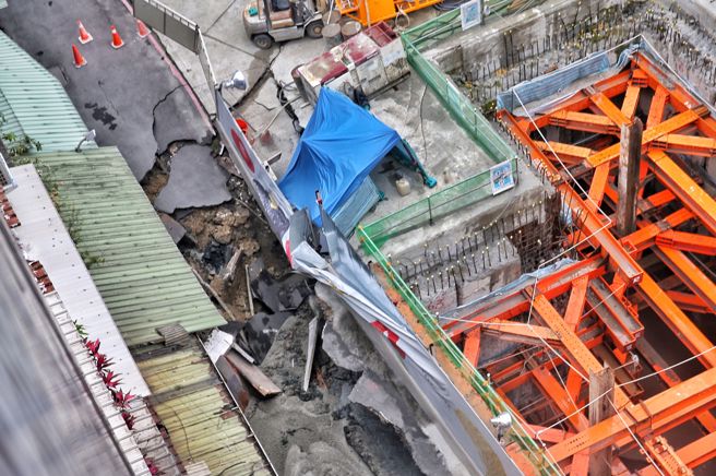 台北市信义区崇德街60巷13日惊传地基严重坍塌，路面上出现巨大天坑，以致一旁住宅有倒塌危机，台北市建筑管理工程处指出，此工程是因连续壁施作，已派员至现场了解处理，目前除连续壁渗水，工地正在止水中。（杜宜谙摄）