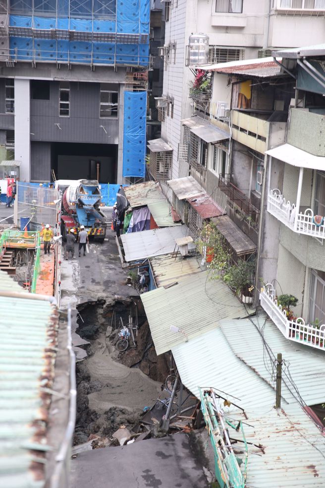 台北市信义区崇德街60巷13日惊传地基严重坍塌，路面上出现巨大天坑，以致一旁住宅有倒塌危机，台北市建筑管理工程处指出，此工程是因连续壁施作，已派员至现场了解处理，目前除连续壁渗水，工地正在止水中。（杜宜谙摄）