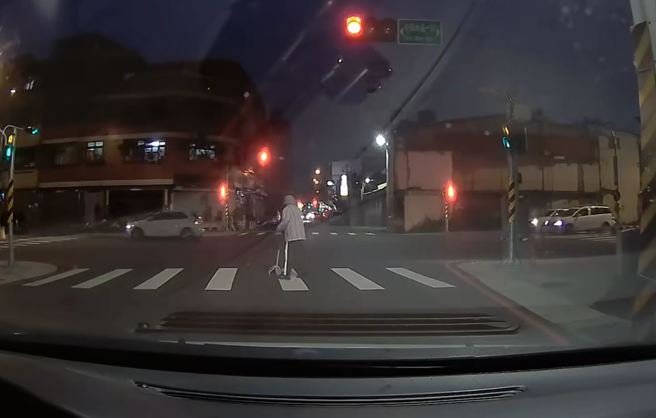 拄拐杖婦被賓士休旅車嚇到後，頻頻回頭看有沒有來車才往前繼續走。（翻攝自臉書爆料公社）