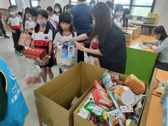 台中龙井区龙港国小学生16日踊跃响应食物传爱活动，不一会儿就装满了食物银行人员带来的两大箱纸箱。（潘虹恩摄）