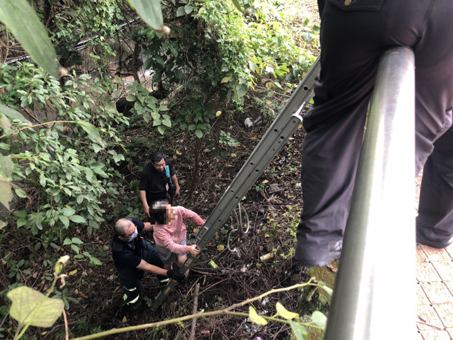 警方在中和街復兴公园旁磺港溪中，发现胡妇神情恍惚、独自站立在溪床角落，员警立即通知消防队及家属到场，以铁梯助其脱困。（图／警方提供）