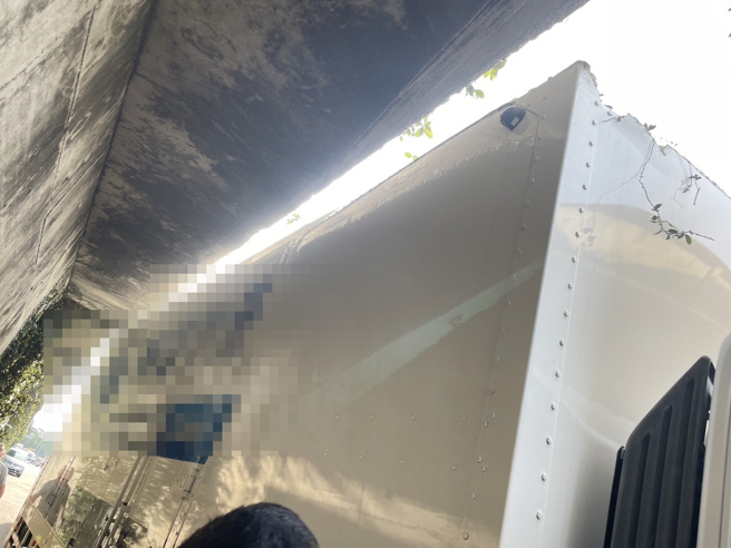 美堤公园引道延伸进入车道突出水泥基座，卡住货车在下方侧倾动弹不得。(戴志扬翻摄)