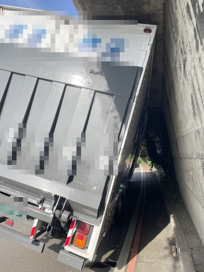 美堤公园引道延伸进入车道突出水泥基座，卡住货车在下方侧倾动弹不得。(戴志扬翻摄)