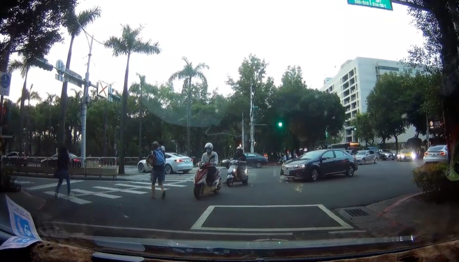 中年男子牵着幼童在巷口准备过马路，眼见号志是红灯，男子仍一把抱起幼童「闯红灯度衝过斑马线」，跑到一半时还差点被机车撞上。（翻摄自脸书「爆料公社」）