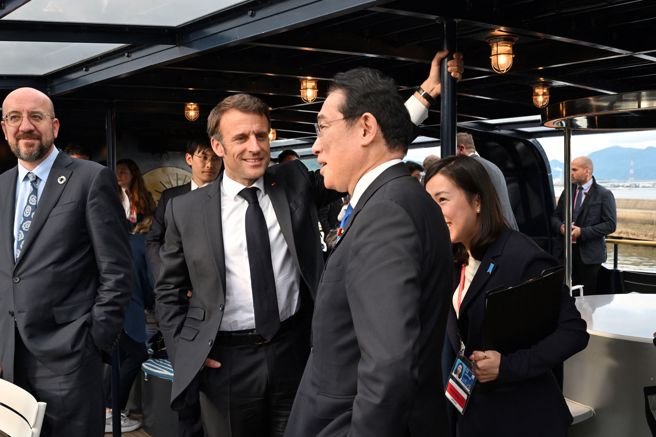 乘船赴严岛神社途中，马克宏与岸田文雄交谈，神色轻松。（路透）