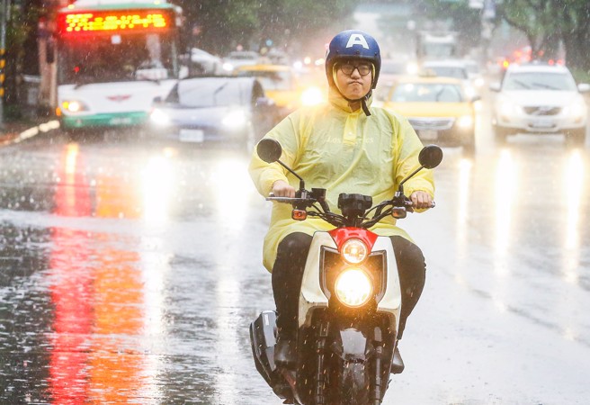 机车骑士冒着大雨疾驶过马路。（粘耿豪摄）