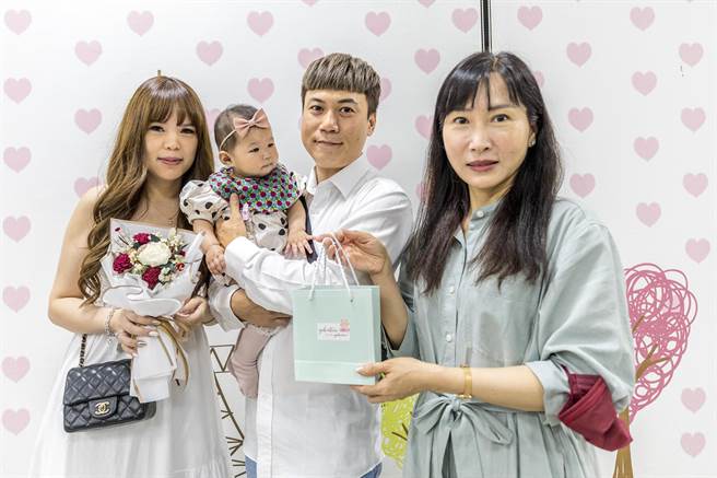 蔡盛文和庄宜萱在竹北户政所登记结婚，高兴抱起友人的小宝贝，户政所主任陈建淳赠给新婚小礼物。（罗浚滨摄）