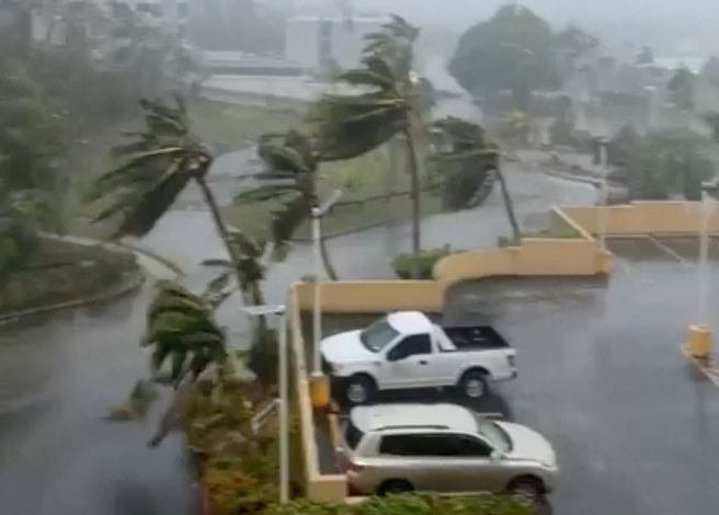 中颱玛娃侵袭关岛，棕榈树被吹得东倒西歪，民眾躲进屋里避难。（图／路透社）
