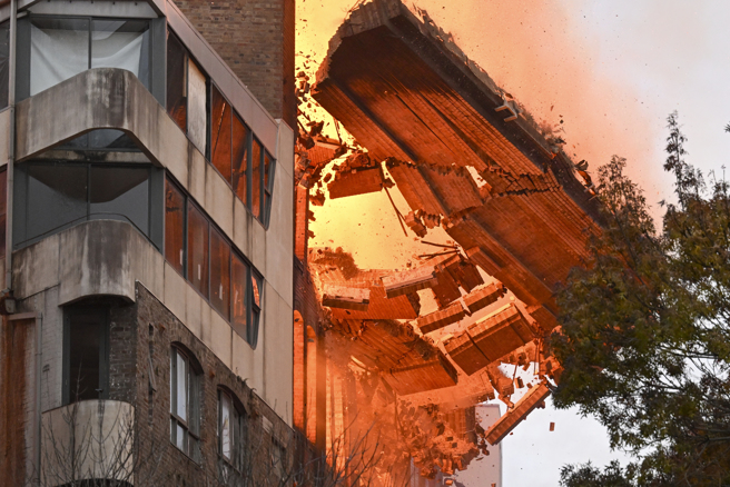 澳洲大城雪梨市中心靠近中央车站一栋老建物25日发生大火，楼顶外墙崩塌，场面十分骇人。（美联社）