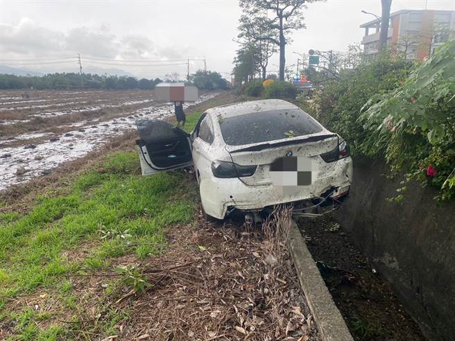 台南21岁吴姓男子26日驾驶百万名车BMW载24岁宋姓女友出游行经台1线434K时，因遇雨天导致车辆失控打滑，先撞上路树后穿越矮木丛滑进路旁水沟卡住。（警方提供／谢佳潾屏东传真）