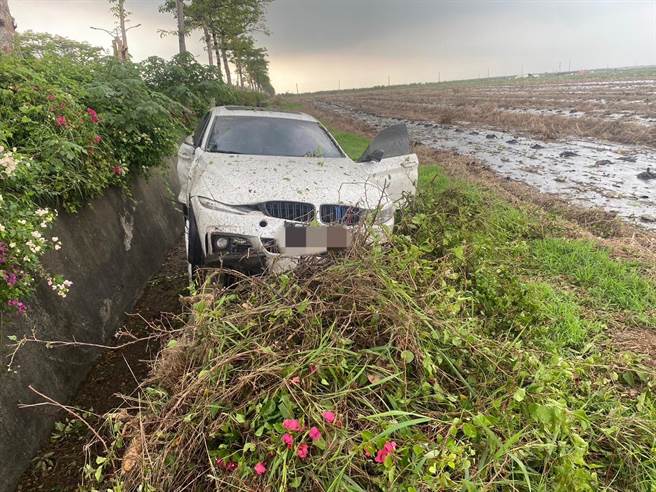台南21岁吴姓男子26日驾驶百万名车BMW载24岁宋姓女友出游行经台1线434K时，因遇雨天导致车辆失控打滑，先撞上路树后穿越矮木丛滑进路旁水沟卡住。（警方提供／谢佳潾屏东传真）