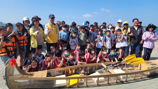 全校师生与来宾开心的在毕业生打造的骨架蒙皮舟前合影留念。（许逸民摄）