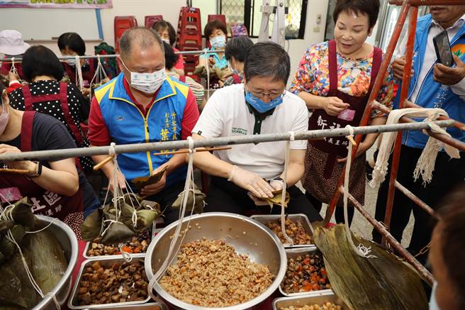 新社社区爱心粽活动一口气要包7500颗爱心粽，县长杨文科（中）也亲自包了几颗。（邱立雅摄）