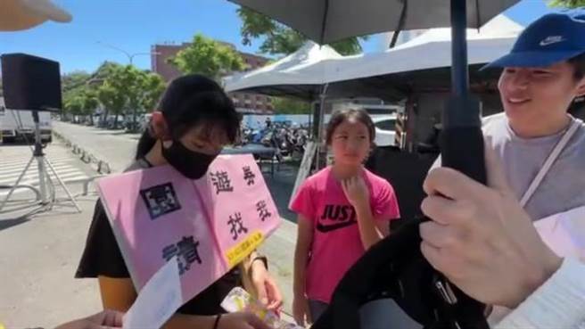 创世基金会台东院主办公益园游会今天登场，场边1对年轻夫妻向1位小小志工购买园游券，却又将券塞回小志工手中。（蔡旻妤摄）