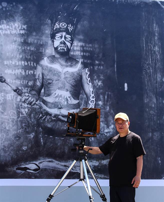 摄影家林添福于展览海报前留影。林添福1960 年出生于台湾新北市。曾任大地地理杂志专任摄影，时尚杂志《VOGUE》《ELLE》中文版特约摄影、 《People》中文版特约摄影。（邓博仁摄）