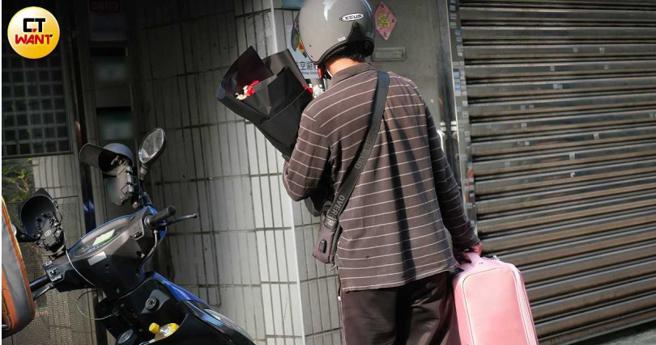 快递公司人员5月25日送来一束红玫瑰以及粉红色行李箱，电话另一头由男性接通。（图／本刊摄影组）