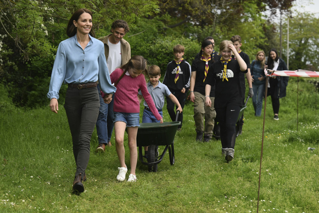 凯特王妃5月8日牵着女儿夏绿蒂公主加入童军营地志工行列，小儿子路易王子兴致勃勃推着独轮车前进。（美联社）