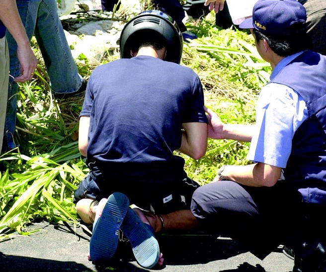  弃尸共犯沈邦桐，在检警寻获尸体时，于公墓下跪对着尸体忏悔。（本报资料照片）