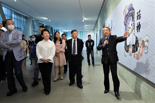 台中市长卢秀燕（左前二）、亚大创办人蔡长海（左前一）、亚大校长蔡进发（左前三）与贵宾，听取亚大现代美术馆馆长潘襎（右）介绍学生创作获国际大奖10神仙的菇神。（亚大提供／陈淑芬台中传真）