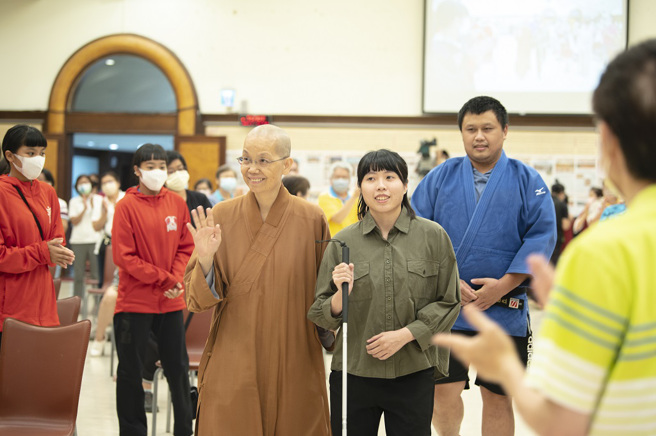 讲师2021东京帕运台湾视障柔道选手李凯琳（右）在中区总住持觉居法师（左）陪同下，持白手杖入场。（图／惠中寺提供）