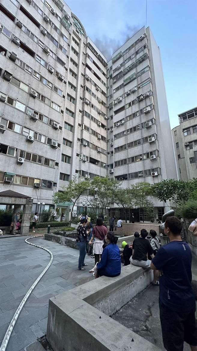 台中市西屯区大楼传出火警，许多住户被疏散，坐在中庭等候。（民眾提供）
