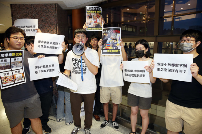 国民党总统参选人侯友宜8日前往政治大学与学生座谈，场外有学生手持标语抗议，质疑侯的选举行程狂拉票，却不管新北幼儿园喂药案。（姚志平摄）