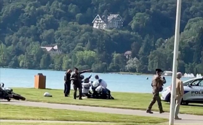 法国东南部小镇湖畔公园8日发生持刀攻击案，警方把凶嫌按倒在地逮捕。（路透）