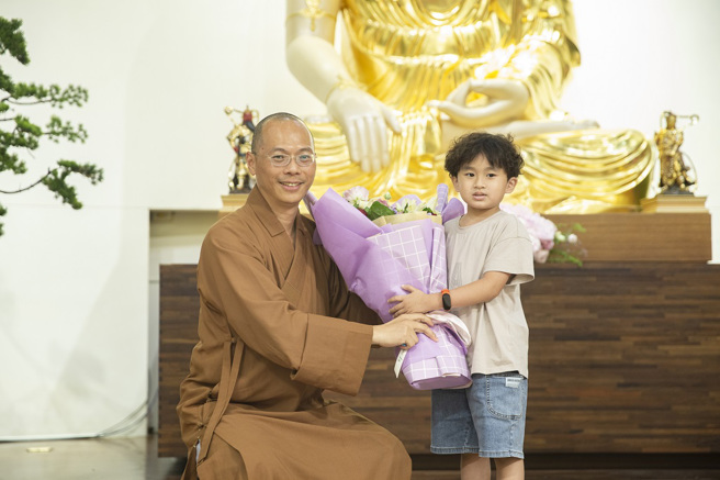 从台北搭高铁特地南下听讲座的6岁小粉丝严琮翔，献花给慧知法师。(图/惠中寺提供)