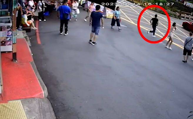 女導遊疑似對一輛紅色馬自達規勸不該駛進老街，還用口哨提醒其他遊客小心車輛，此舉惹怒駕駛，男駕駛突然從遠處下車後，朝導遊飛奔並出腳踢人。（翻攝自臉書「爆料公社」）