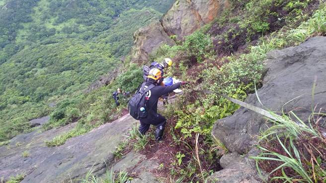 ▲設備架設好後，搜救隊員引導民眾，順利安全攀爬下山。（新北市消防局提供／徐佑昇新北傳真）