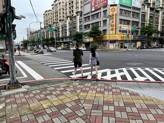 建中路与建功一路口的人行道直接衔接槽化线，行人只能跨越槽化线。（王惠慧摄）