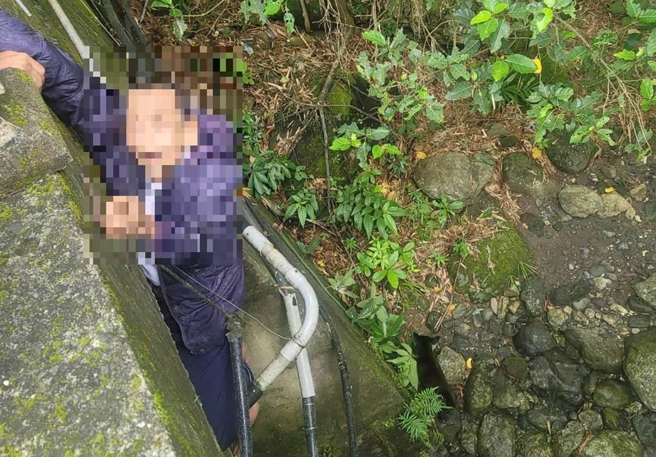 受困老翁双脚卡在桥边水管与桥梁之间无法移动，仅用1只脚坐在水管上以防止掉落，情况危急。（台东县警察局提供／萧嘉蕙台东传真）