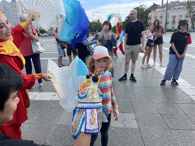 外国小朋友手拿布袋戏偶，试着练习操作。（纸风车剧团提供）