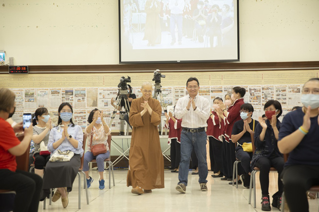 佛光山中区总住持觉居法师(左)偕同讲师吴家德步入大雄宝殿讲台，受到热烈欢迎。（图／惠中寺提供）