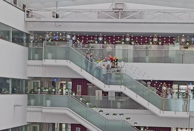 今天上午近10點有名身著紅衣的女子坐在文心樓10樓到9樓的樓梯圍欄欲輕生，警方及市府主管聯手將她勸回。（取自爆料公社）