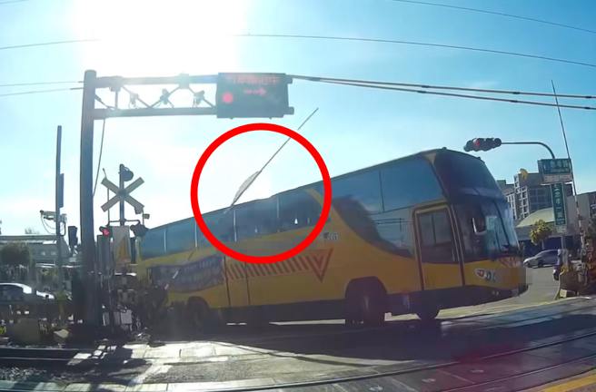 平交道铃声响起，栅栏缓缓放下时，当地一间私立中学的校车疑似为抢快竟强行通过，导致栅栏当场撞上车顶，触发列车防护系统。（翻摄自脸书「爆料公社」）
