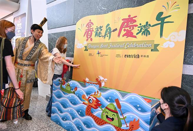 端午節連假即將展開，桃機昇恆昌免稅商店21日特別舉辦「賽龍舟、慶端午」活動，由工作人員打扮成屈原，向外國遊客講解端午節的由來，並體驗陸上賽龍舟活動，讓出國旅客感受端午節日氛圍。（陳麒全攝）