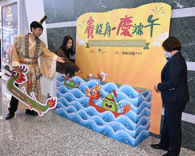 端午節連假即將展開，桃機昇恆昌免稅商店21日特別舉辦「賽龍舟、慶端午」活動，由工作人員打扮成屈原，向旅客講解端午節的由來，並體驗陸上賽龍舟活動，讓出國旅客感受端午節日氛圍。（陳麒全攝）
