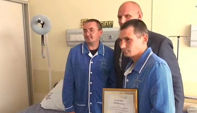 俄国士兵克拉夫佐夫(右)因击毁乌克兰的豹式坦克而获奖金与奖状。中间者是颁奖人奥运摔角选手卡列林，最左是同病房伤患。(图/ZVEZDA NEWS)