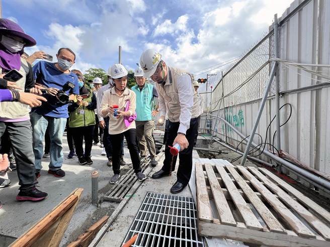 台南市长黄伟哲巡查疫情热区仁德区建筑工地的登革热防治措施，并协助在工区内排水沟放置灭蚊药。（洪荣志摄）