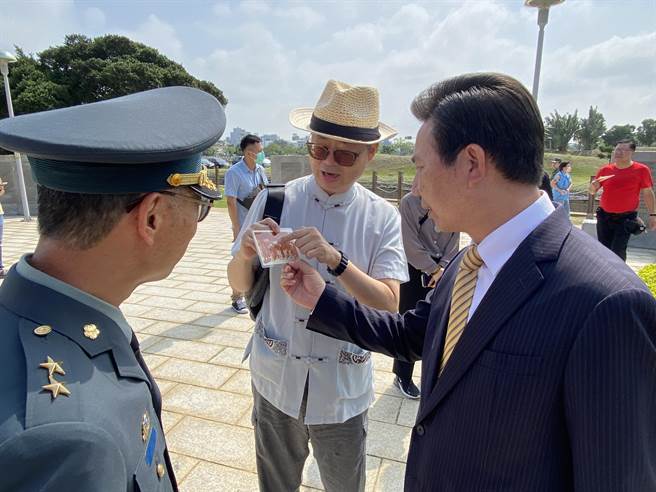 胡璉將軍孫兒胡敏越(中)向縣長陳福海(右)與金防部指揮官陳忠文中將(左)解說兒時與祖父於金門時的照片。(于家麒攝)