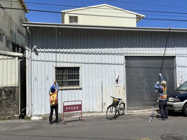 防疫志工拿長竹竿在民宅天溝投藥，引來民眾狐疑眼光，里長鄭晴而沿街廣播「這是志工不是怪叔叔」。（曹婷婷攝）