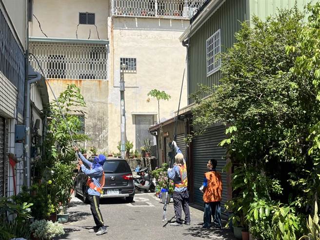 防疫志工拿長竹竿在民宅天溝投藥，引來民眾狐疑眼光，里長鄭晴而沿街廣播「這是志工不是怪叔叔」。（曹婷婷攝）