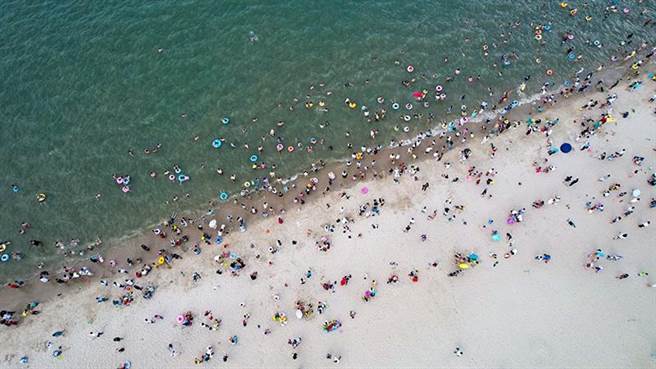 图为6月22日，游客在海南海口假日海滩「洗龙水」。（图／新华社）。