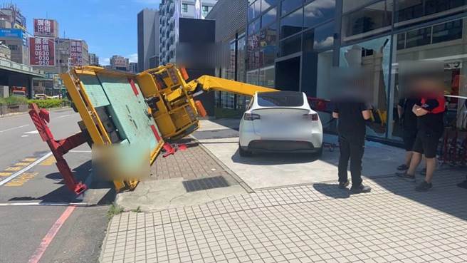 吊车吊挂特斯拉时翻覆，撞破一面落地窗。（警方提供）