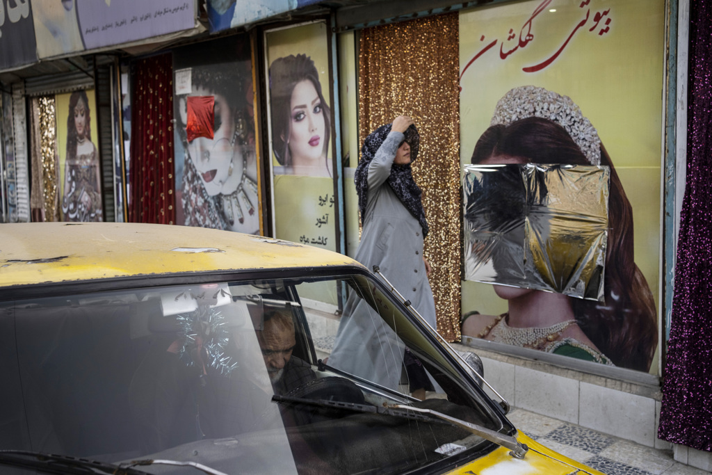 2021年9月12日，阿富汗首都喀布尔一名妇女走过窗户上的装饰品被涂抹的美容院资料照。（路透社）(photo:ChinaTimes)