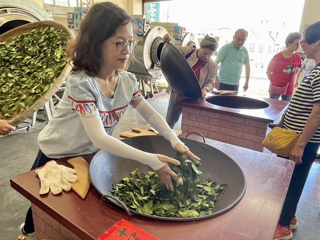 港澳旅客站在高温炉灶旁，体验古法炒茶方式。（杨静茹摄）